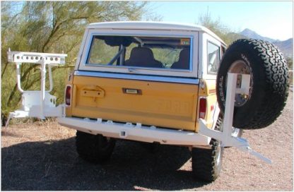 A yellow and white truck with a tire on the back.